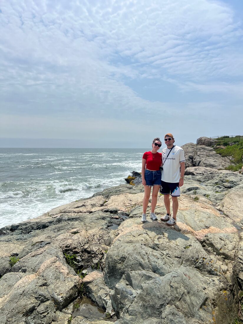 Katrina and Matthew standing on coastal rocks by the ocean